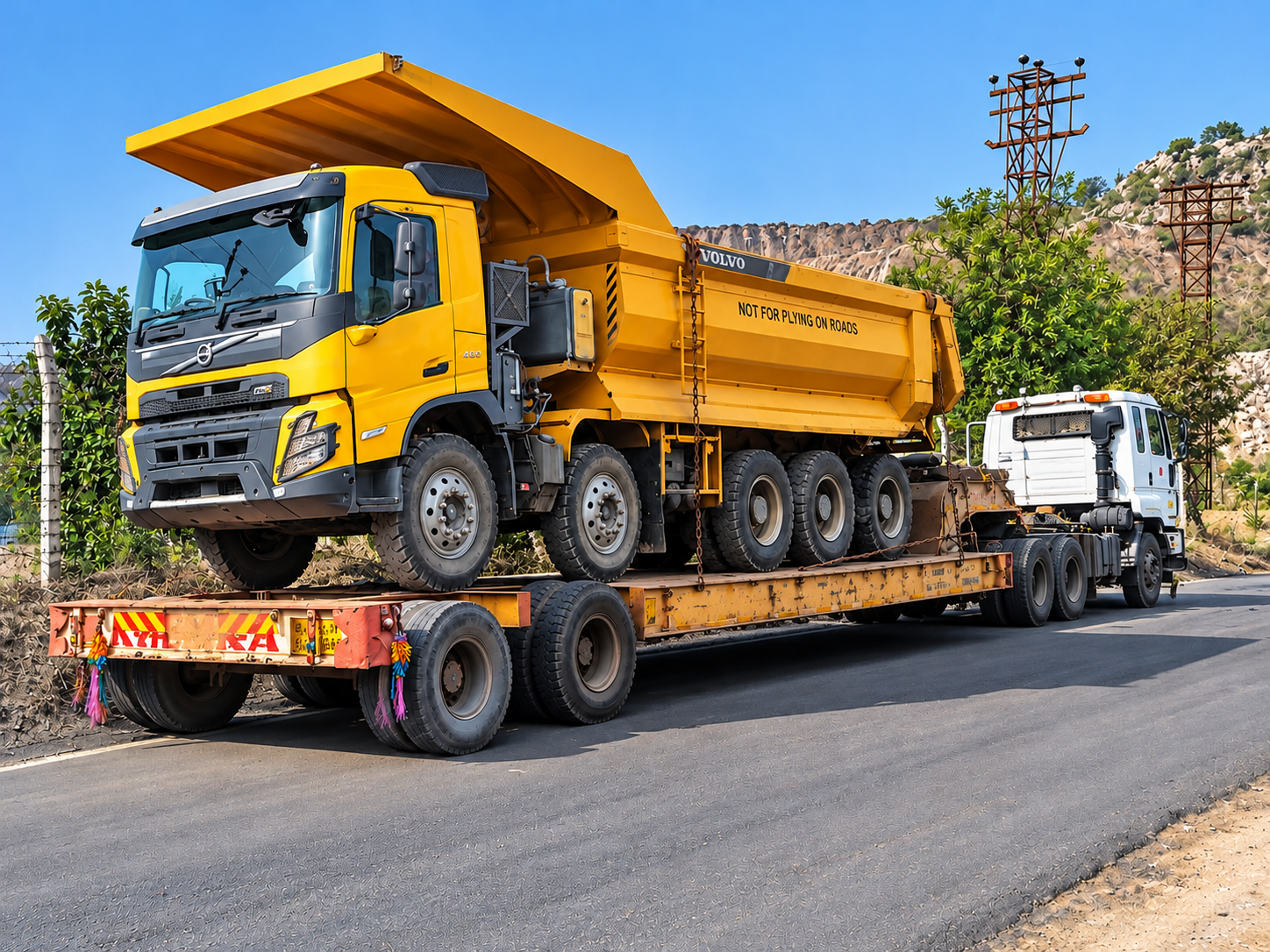 A heavy earth mover strapped to a hydraulic low bed trailer